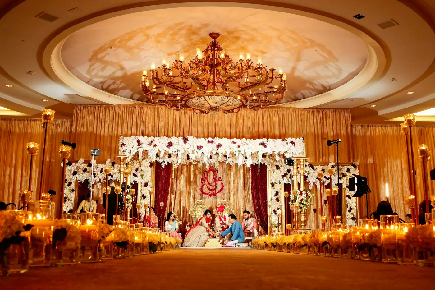 Stock inspiration photo of an Indian wedding ceremony in a ballroom with a flower-covered stage; not a Safe Events project photo.