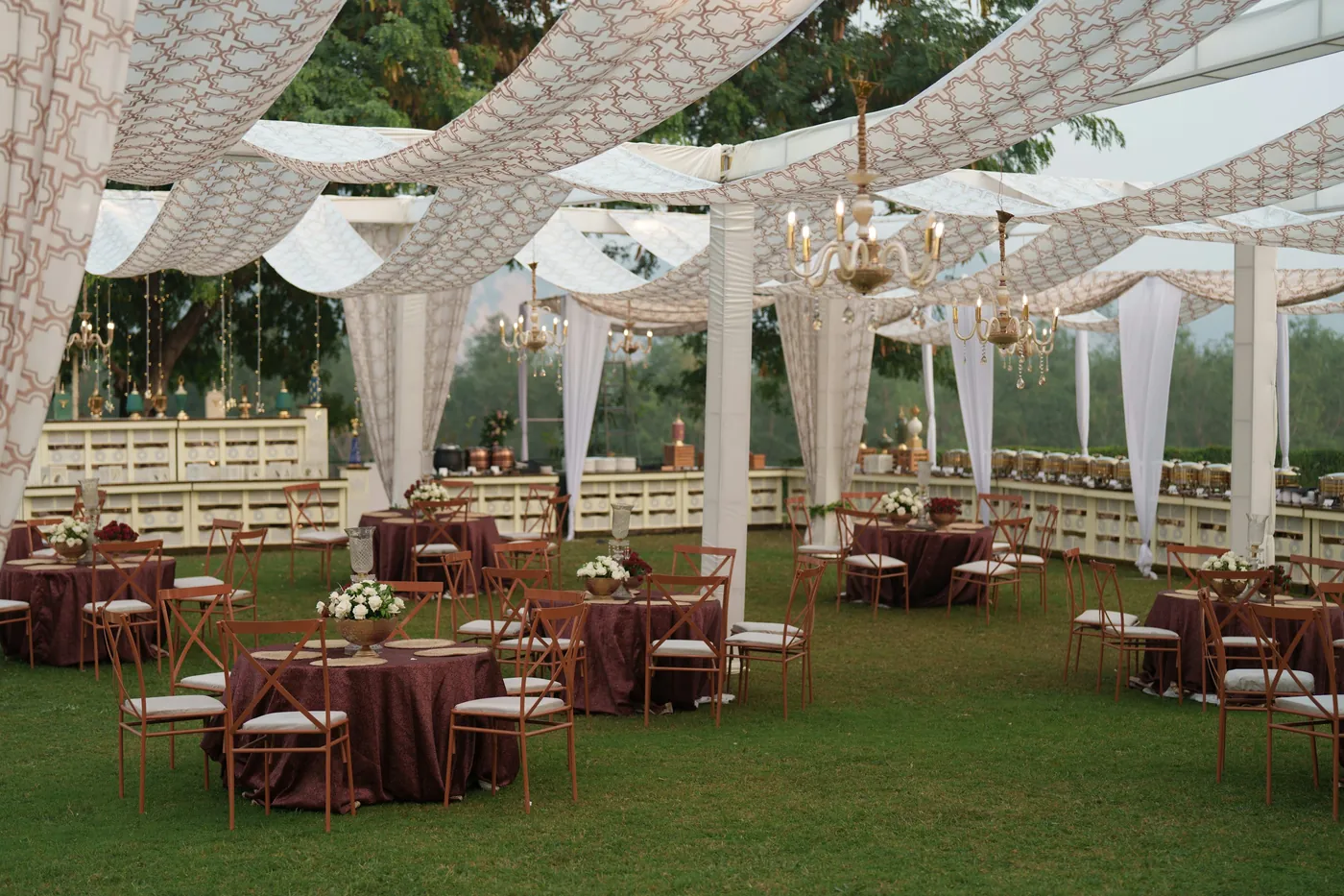 Outdoor reception tables arranged beneath a white draped canopy.